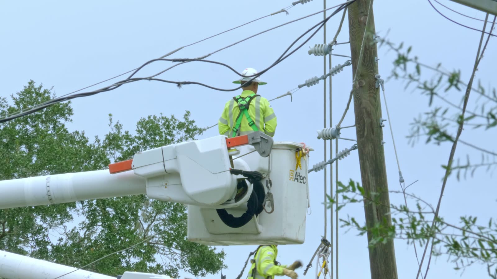 Utility worker in a bucket lift repairing overhead lines