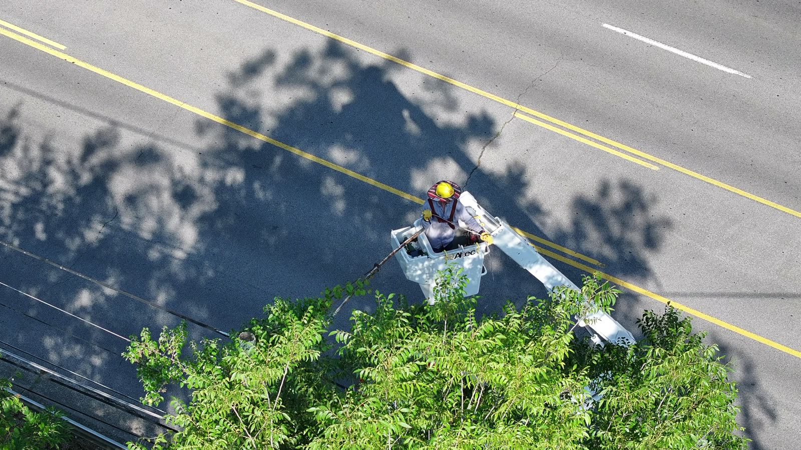 Lineman in an aerial bucket working on power lines, seen from above