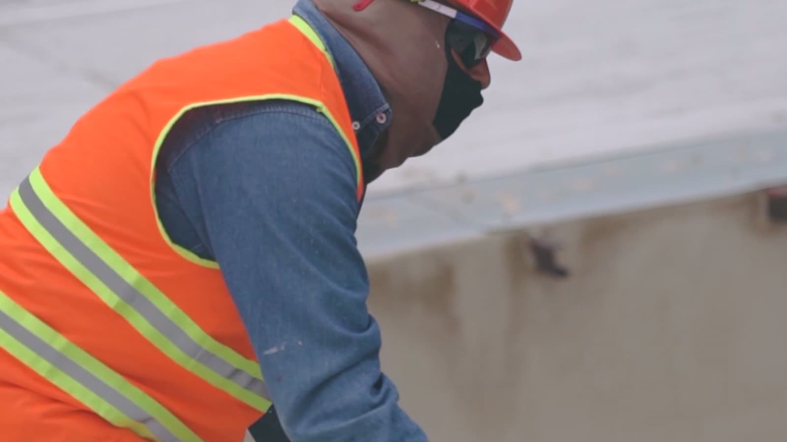 Worker in a safety vest installing rooftop solar panels